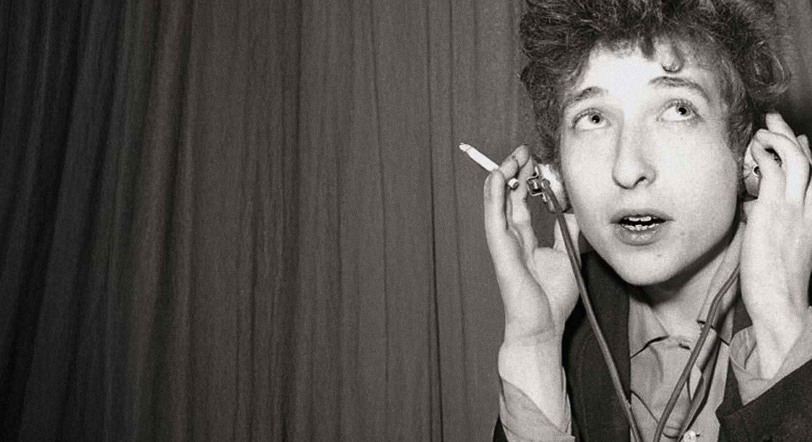 a young Bob Dylan, listening thoughtfully with headphones, a cigarette in his hand